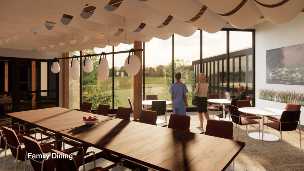 spacious family dining area with a long, dark wood communal table and several smaller round tables. Large windows overlook a green landscape. People are walking and sitting in the bright, modern space, which features unique wave-like ceiling panels and hanging light fixtures.
