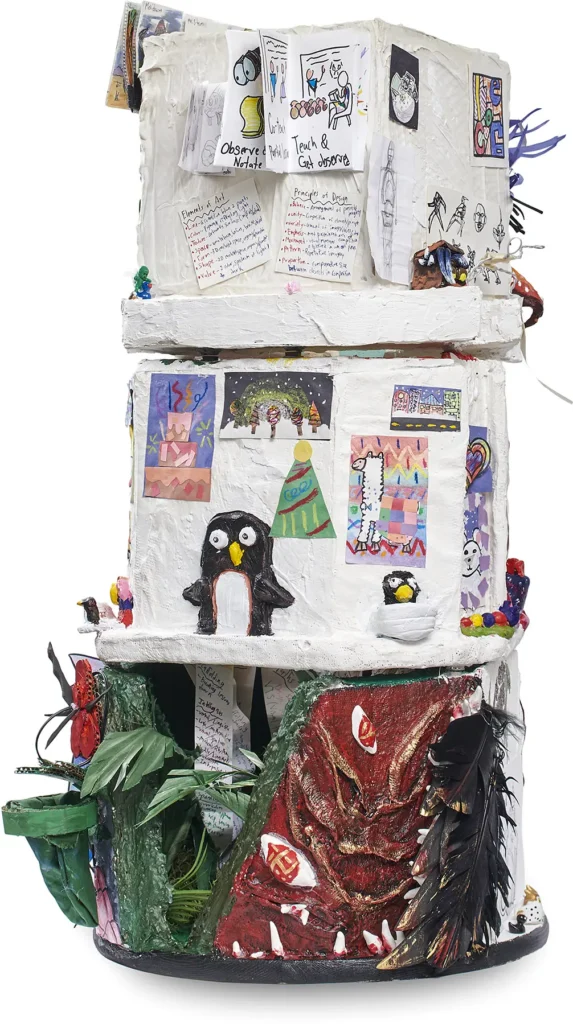 A mixed-media sculptural tower covered in white plaster, decorated with colorful sketches, paintings, small penguin figurines, and a textured red monster base.
